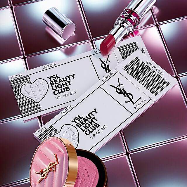YSL Beauty Produkte (Lippenstift und Rouge) arrangiert mit ticketartigen VIP-Zugangskarten auf einer reflektierenden metallischen Oberflache.