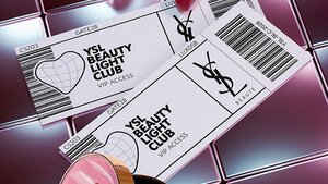 YSL Beauty-Produkte, darunter eine gesteppte Dose, Mascara und zwei Lippenstifte vor glanzendem, rosa gefliestem Hintergrund.