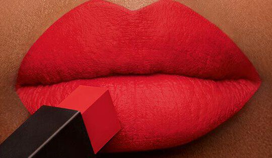 Close-up of luscious red lips with a red lipstick bullet poised against them, showcasing a glossy finish.