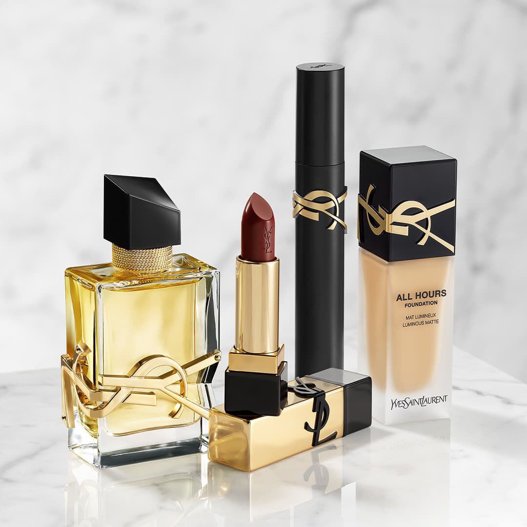 YSL Beauty-Produkte: Parfum, Lippenstift, Mascara und Foundation auf Marmor.