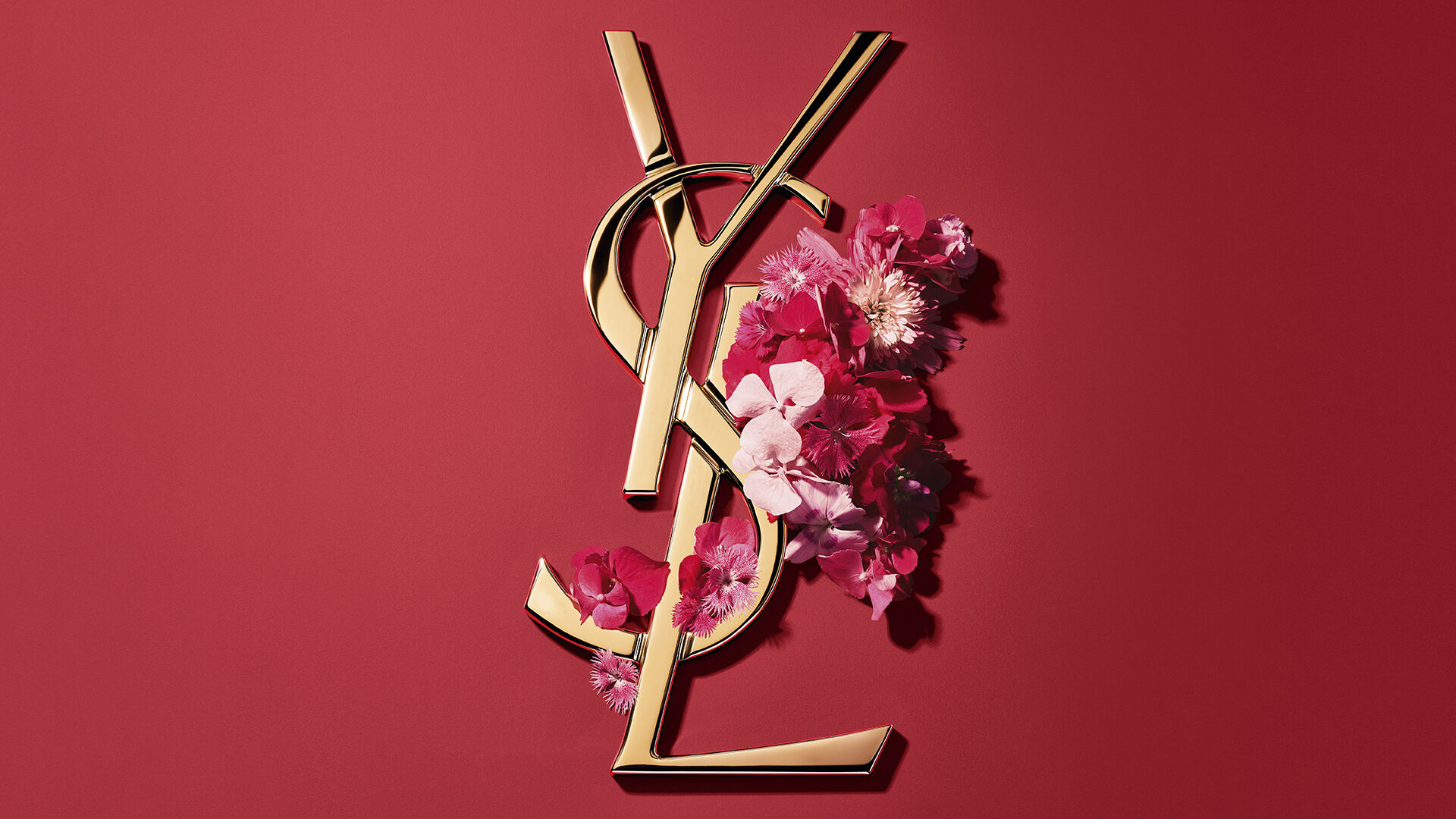 Rote YSL-Geschenkbox mit rosa Blumen auf rotem Hintergrund.