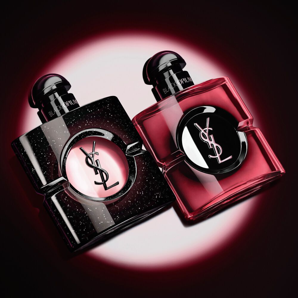 Zwei beleuchtete Yves Saint Laurent Black Opium Parfumflakons vor dunklem Hintergrund.