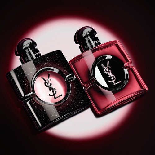 Zwei beleuchtete Yves Saint Laurent Black Opium Parfumflakons vor dunklem Hintergrund.