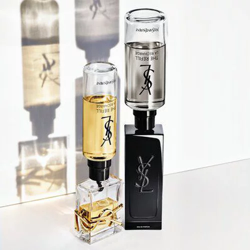 Zwei Parfumflakons von Yves Saint Laurent (einer hell, einer dunkel) mit ihren nachfullbaren Kartuschen.