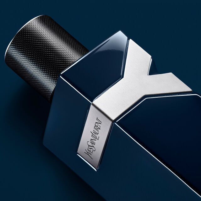A close-up of a sleek blue and silver fragrance bottle with a modern design, featuring a textured black cap and the brand name engraved on the side.