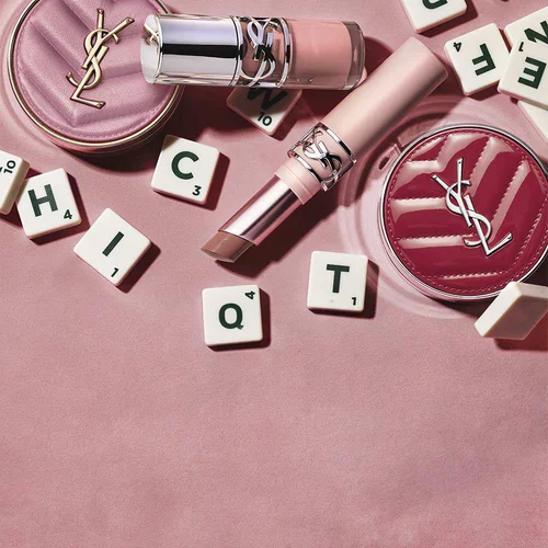 YSL-Make-up-Produkte und Buchstabensteine auf rosa Hintergrund.