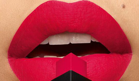 Close-up of vibrant red lips applying lipstick, with the lipstick bullet positioned in front.