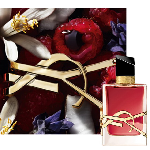 Nahaufnahme des Libre Berry Crush Flakons mit goldenem YSL-Logo, umgeben von roten Beeren und floralen Elementen.