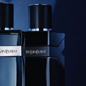 Two black glass fragrance bottles are positioned side by side against a dark background, featuring sleek designs and silver accents.
