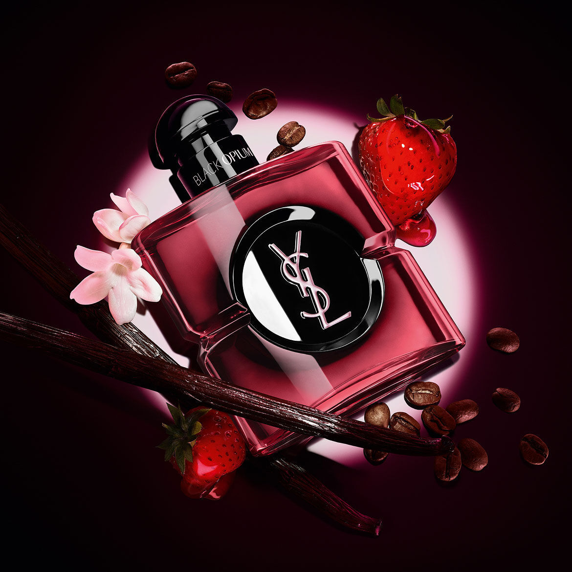 Black Opium Eau de Parfum Pink Glaze Flakon, umgeben von frischen Erdbeeren, Vanilleschoten, Kaffeebohnen und Jasmin.