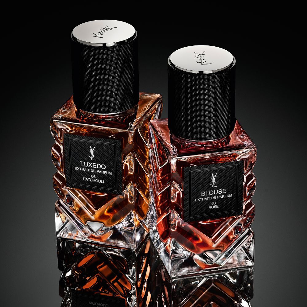 Eine Kollektion von Yves Saint Laurent „Le Vestiaire des Parfums“ Flakons, die rautenformig auf einer reflektierenden schwarzen Oberflache angeordnet sind.