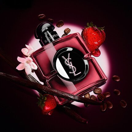 YSL Black Opium Parfumflakon, umgeben von Kaffeebohnen, Erdbeeren, Vanilleschoten und weißen Bluten vor dunklem Hintergrund.
