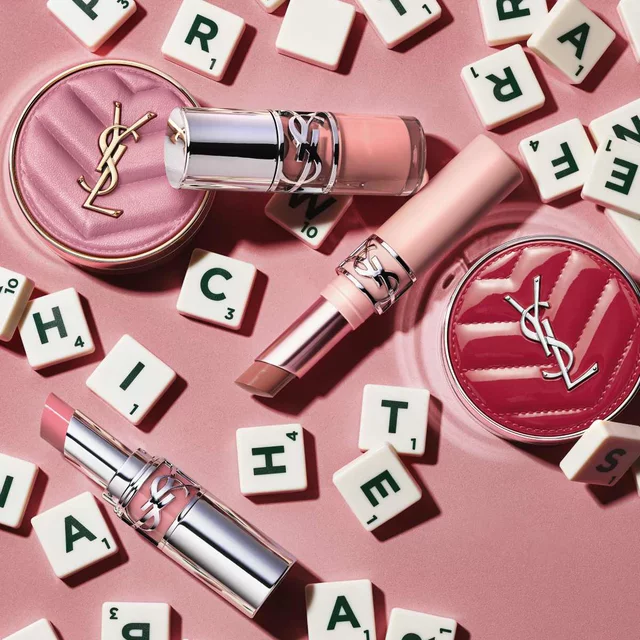 YSL-Make-up-Produkte und Buchstabensteine auf rosa Hintergrund.