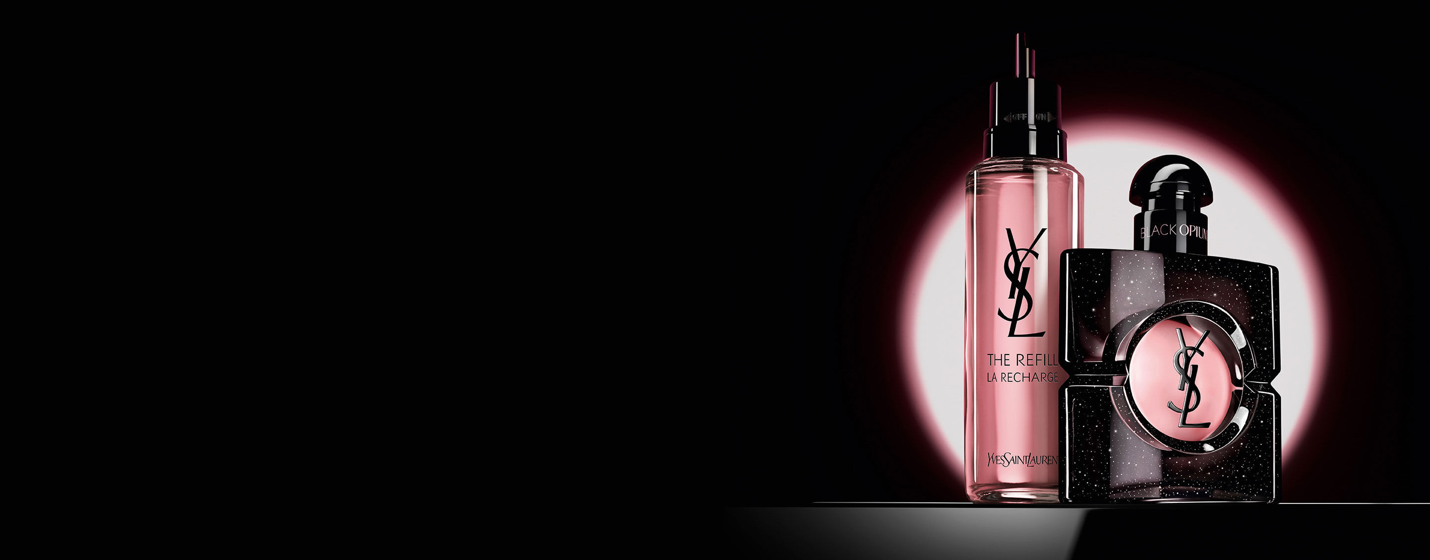 Black Opium Eau de Parfum Flakon neben der 100-ml-Glas-Nachfullflasche mit YSL-Logo.