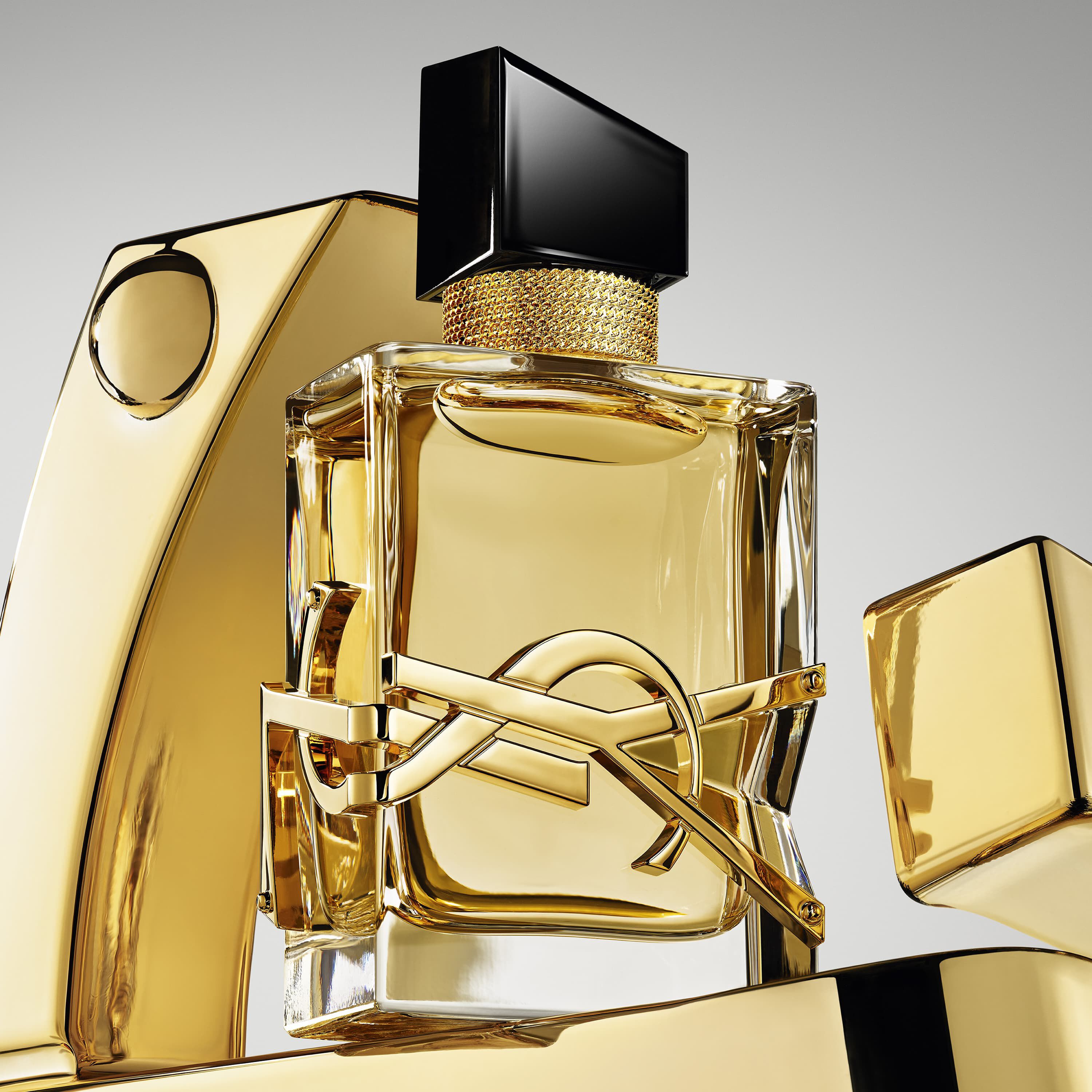 YSL Parfumflakon in Gold mit schwarzer Kappe und Logo, umgeben von goldenen Elementen.
