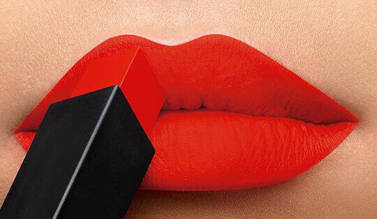 Close-up of vibrant red lips with a lipstick bullet partially applied, showcasing a bold makeup look.