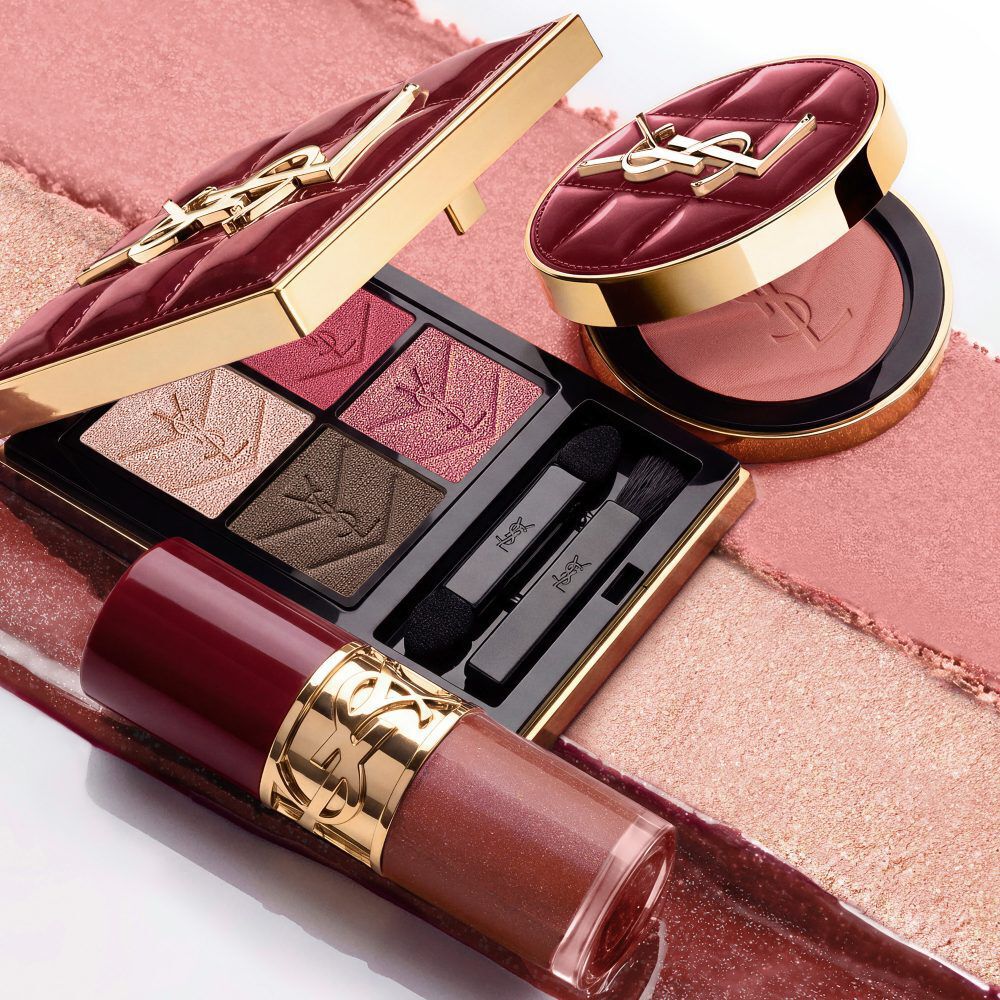 Model in schwarzem Anzug und glamourosem Look, thront in festlichem Kerzenlicht zwischen YSL-Geschenkboxen.