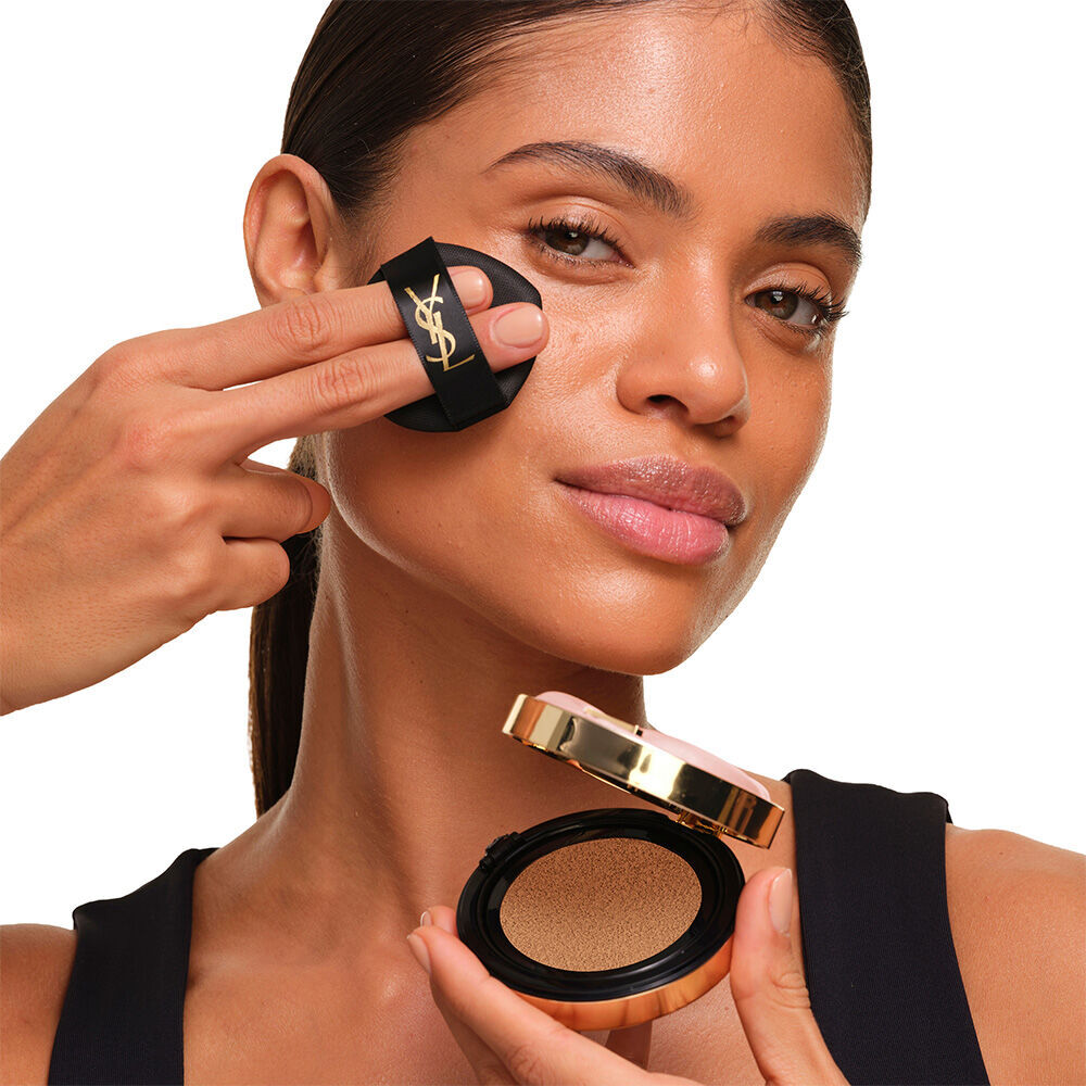 Ein Model mit glatter, strahlender Haut halt das pinke YSL SKIN AFFAIR CUSHION FOUNDATION, um einen naturlichen, leuchtenden, makellosen Teint zu prasentieren.