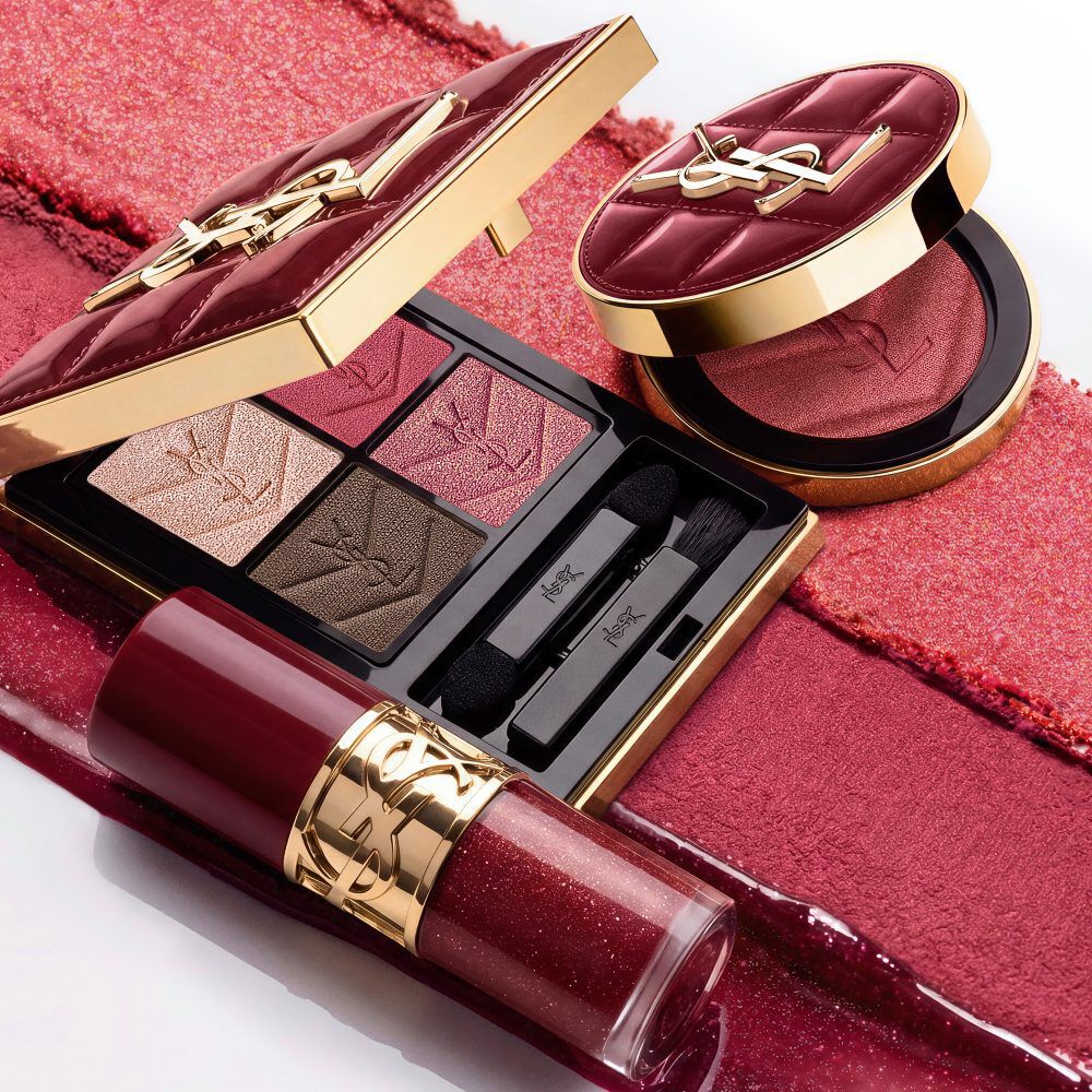 Model in schwarzem Anzug und glamourosem Look, thront in festlichem Kerzenlicht zwischen YSL-Geschenkboxen.