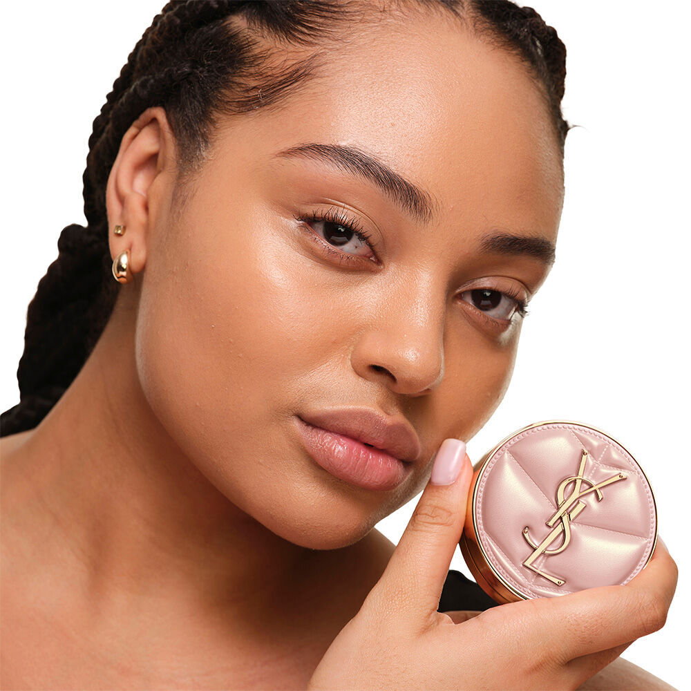 Model mit glatter, strahlender Haut halt das pinke YSL SKIN AFFAIR CUSHION FOUNDATION und prasentiert einen naturlichen, makellosen Glow.