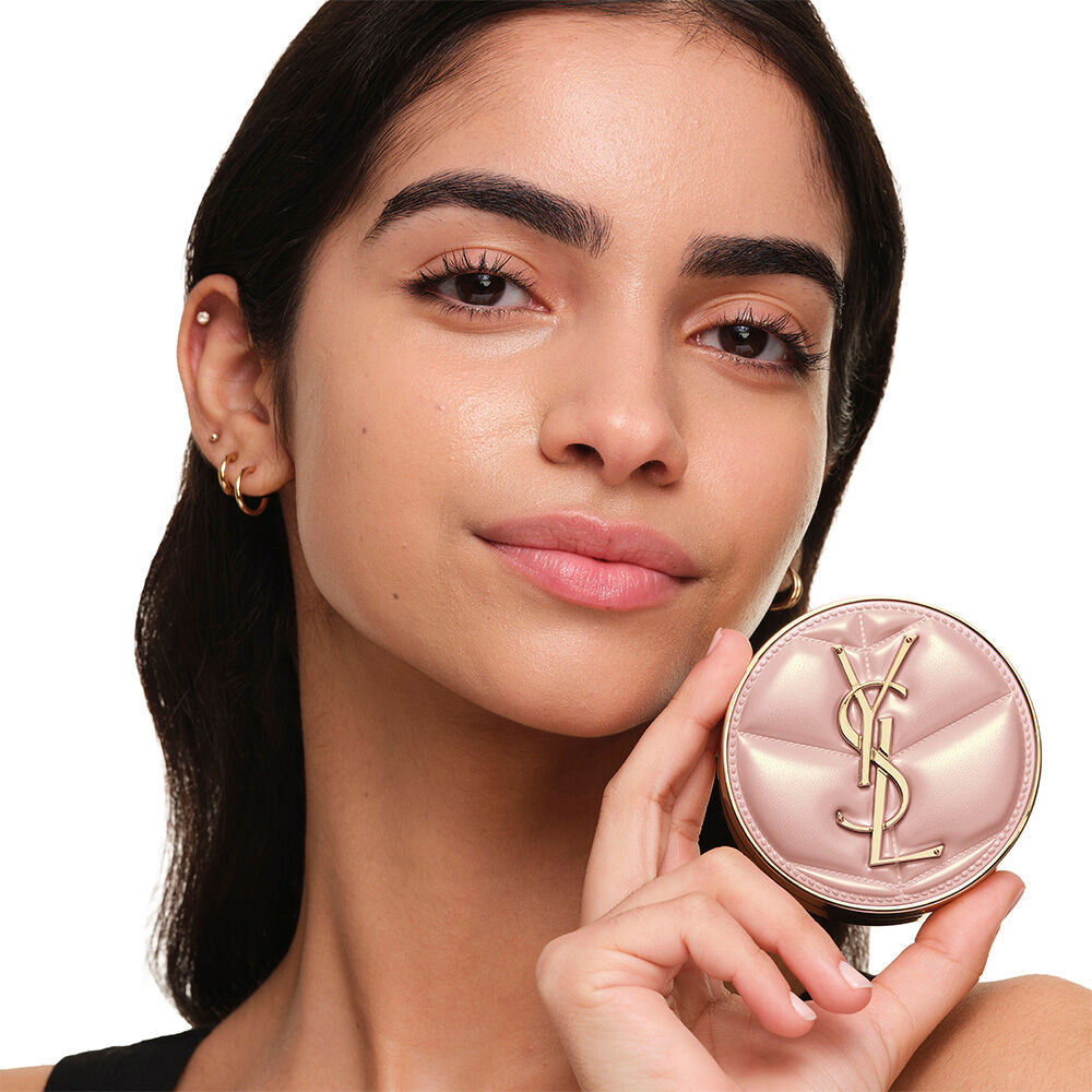 Model mit glatter, strahlender Haut halt das pinke YSL SKIN AFFAIR CUSHION FOUNDATION, um einen naturlich leuchtenden, makellosen Teint zu prasentieren.