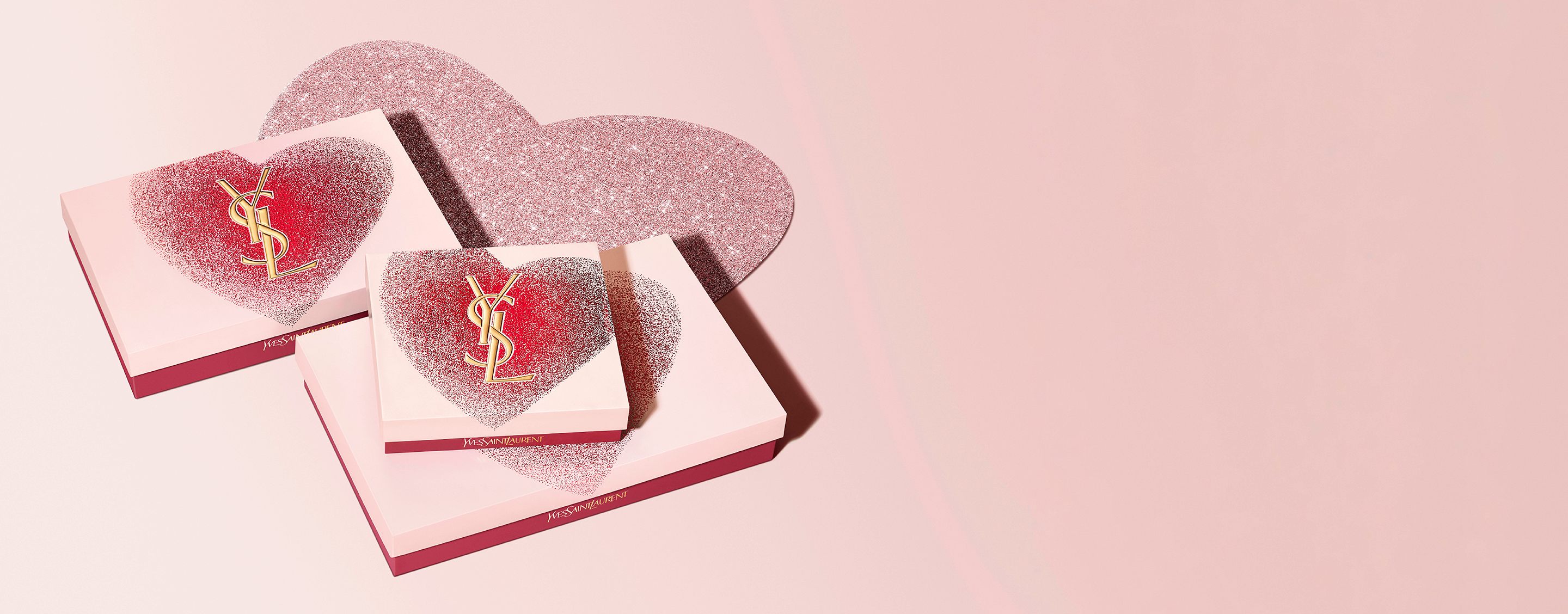 YSL Beauty Valentinstags-Geschenksets in herzförmigen Schachteln mit goldenem YSL-Logo und einem glitzernden roten und rosa Design.