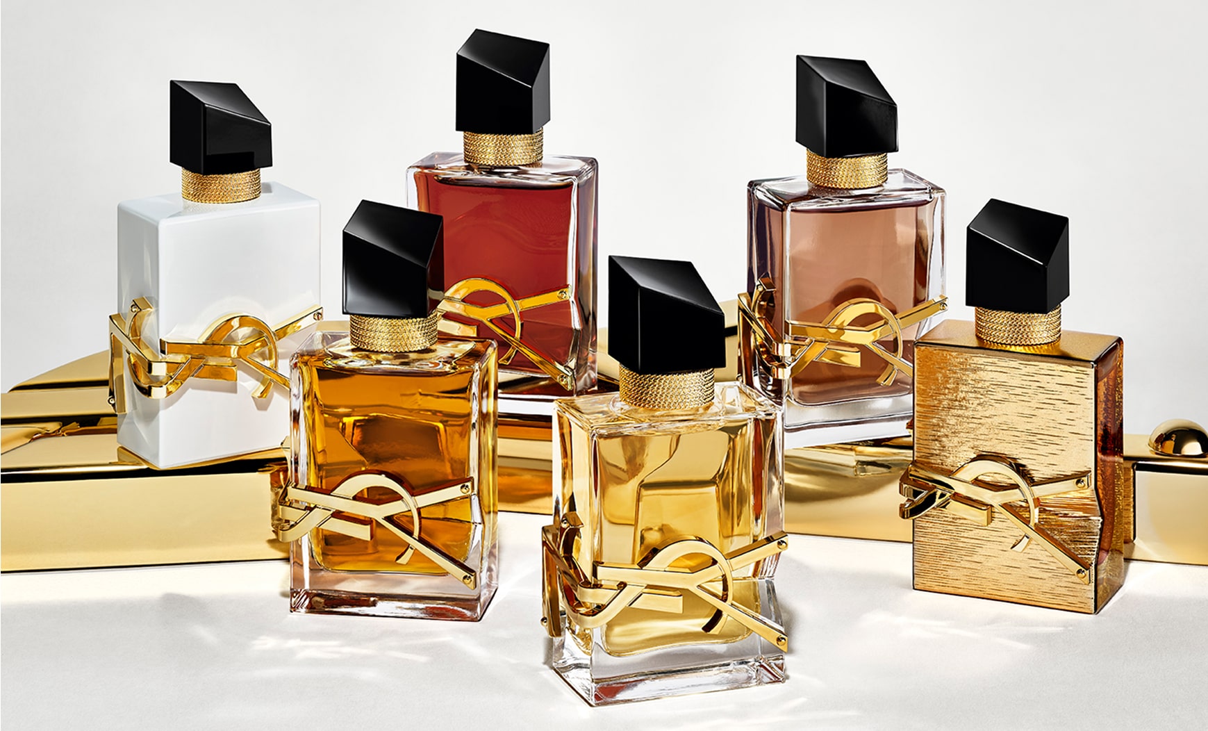 Sechs YSL Libre-Parfümflakons präsentierten sich auf einer glänzenden Goldoberfläche. Die Flakons zeigen Variationen in der Farbe der Flüssigkeit und der Oberfläche, darunter klare, weiße, rötliche und braune Farbtöne sowie einen strukturierten, ganz aus Gold gefertigten Flakon. Alle Flakons tragen den ikonischen goldenen YSL-Schriftzug und einen schrägen schwarzen Verschluss.



