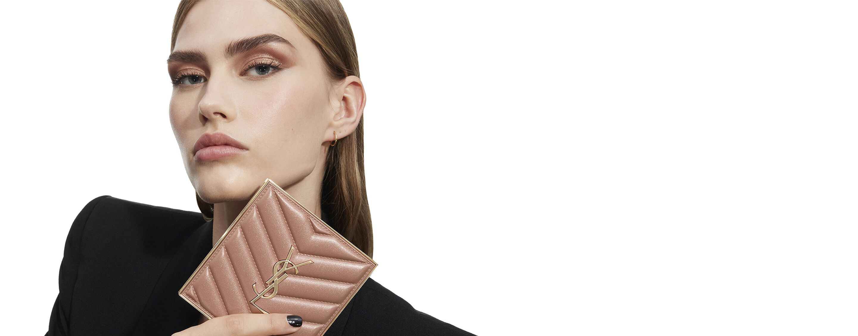 Eine Frau mit einem schimmernden Make-up-Look in Roségold hält eine passende, gesteppte Lidschattenpalette von Yves Saint Laurent in den Händen.