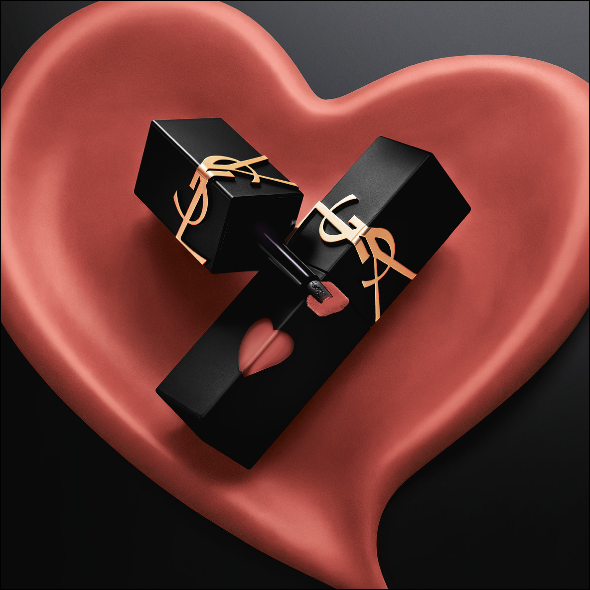 Two YSL lipsticks resting inside a pink sculpted heart.