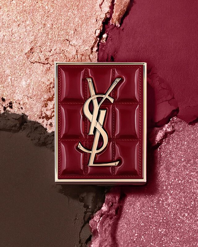 YSL Couture Mini Clutch Palette vor einem strukturierten Hintergrund aus schimmernden Lidschattenpigmenten in #1982 Burgundy Millesime.