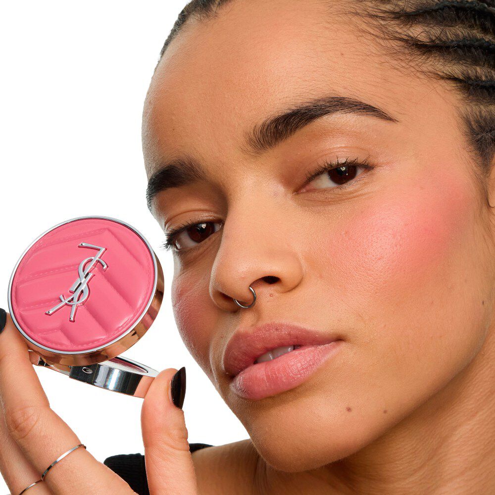 Nahaufnahme einer Model, die den YSL Make Me Blush Lifted Glow Cream Blush hält – strahlender, angehobener Glow auf den Wangenknochen. mieux