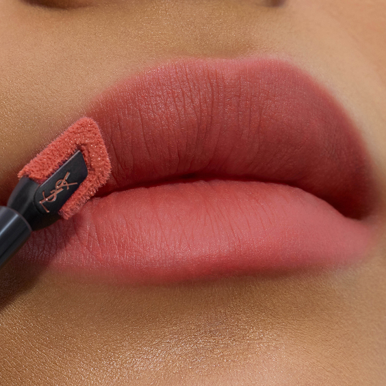 Nahaufnahme weicher, matt-rosiger Lippen, die präzise mit dem abgewinkelten, flachen Applikator des YSL Lippenstains konturiert werden.