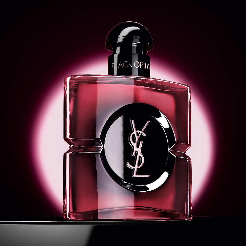 Black
                Opium Eau de Parfum Pink Glaze Flakon, hervorgehoben durch einen pinken,
                kreisförmigen Schein auf dunklem Hintergrund.