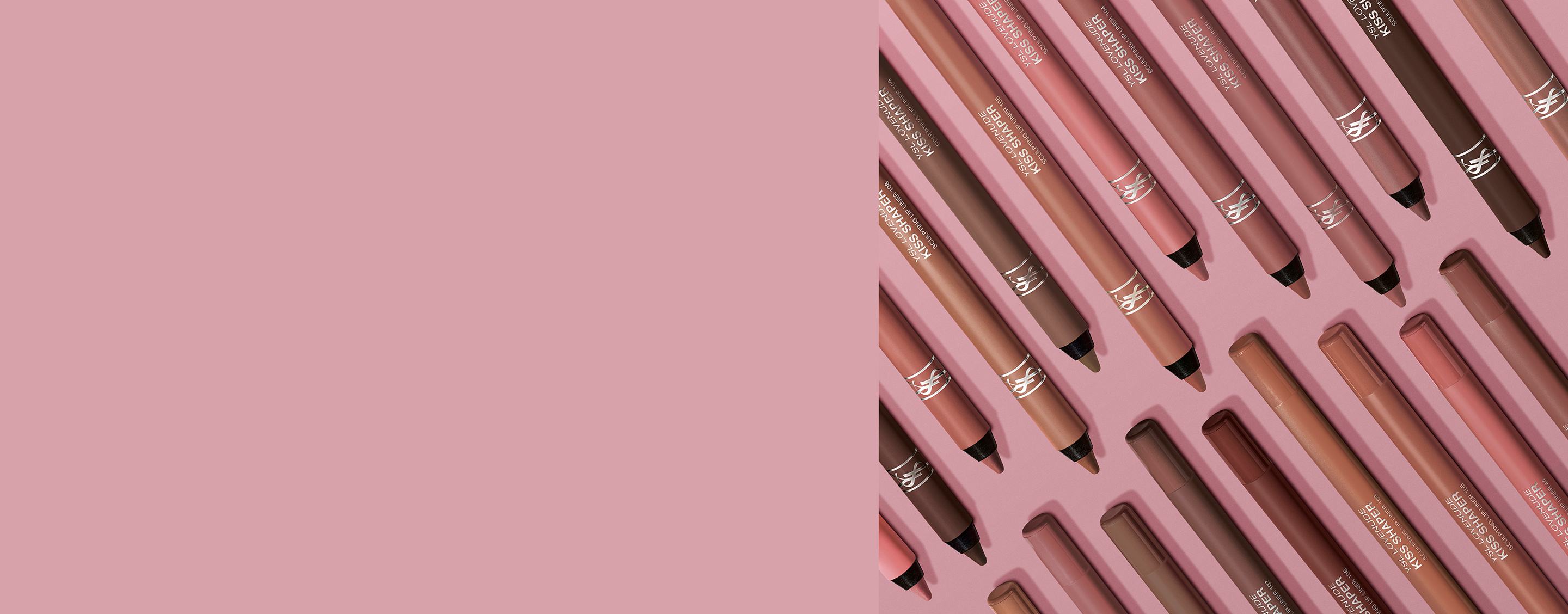 Auswahl an YSL Kiss Shaper Lippenkonturenstiften in Nude- und Brauntönen auf rosa Hintergrund.