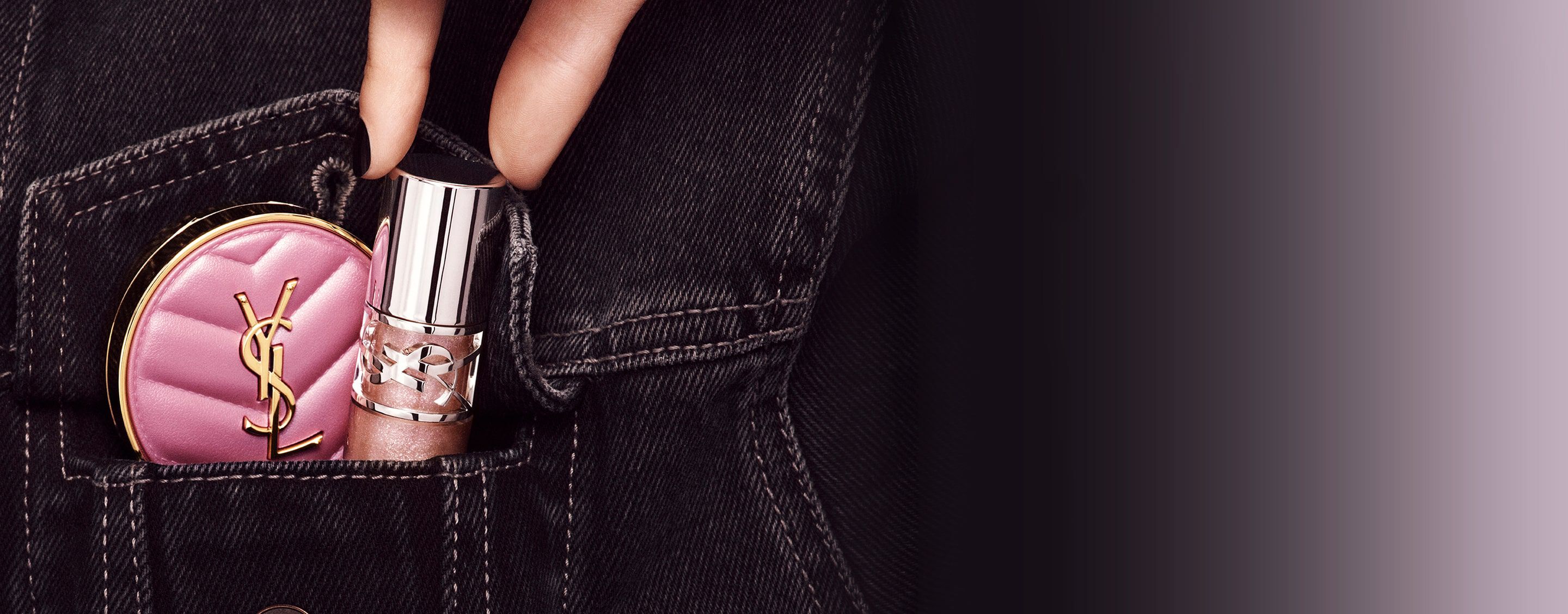 Eine Hand steckt das YSL LOVESHINE Lip Oil Gloss und das rosa Make Me Blush Kompakt-Rouge in eine Jeanstasche