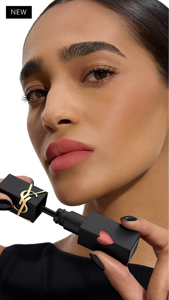 Modell mit tief-mittlerem Hautton, das einen weichgezeichneten Matt-Lippenlook trägt und den Applikator von YSL THE INKS BLUR Lip Stain neben ihr Kinn hält.