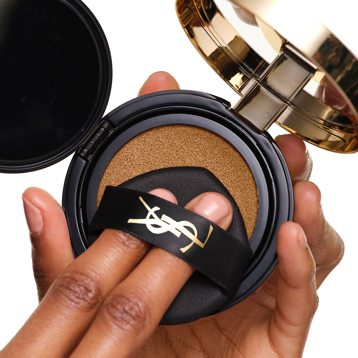 Das YSL SKIN AFFAIR SOFT GLOW CUSHION wird geladen. Finger unter das schwarze Logo-Band drücken den Makeup-Applikator.