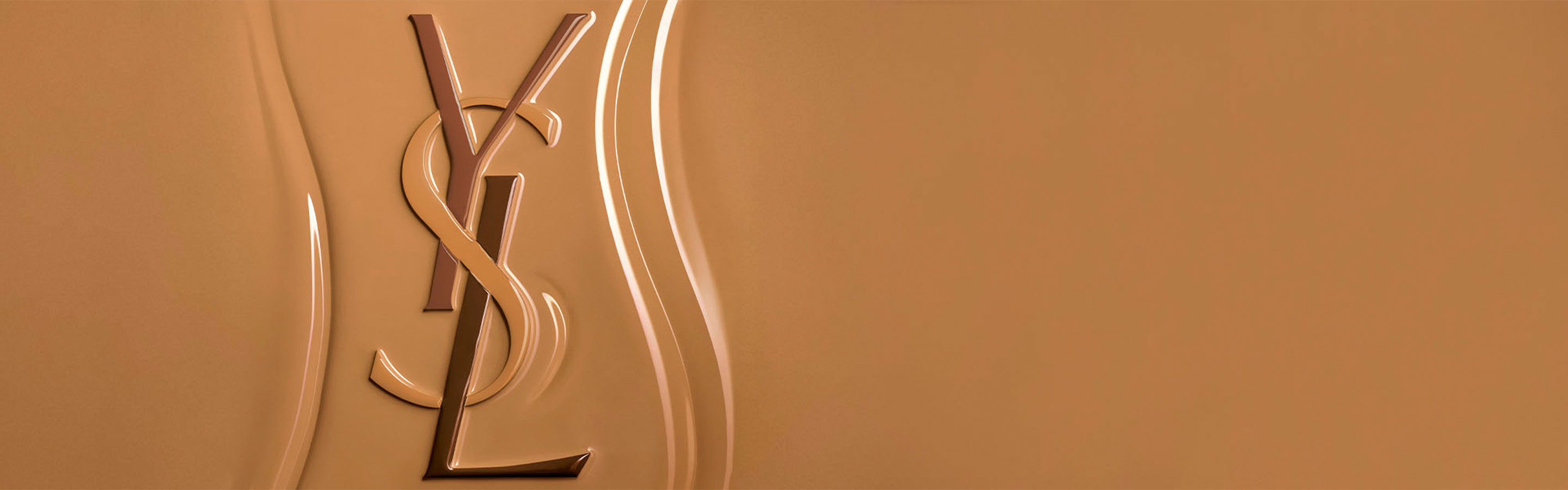 Yves Saint Laurent (YSL) Logo in Relief auf einer texturierten Oberfläche von flüssigem Make-up, das die reichhaltige und leicht verblendbare Textur des Produkts hervorhebt.